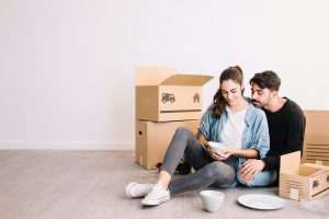 couple-with-smartphone-front-moving-boxes