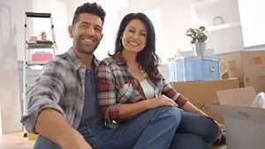 Young couple in new home surrounded by moving boxes
