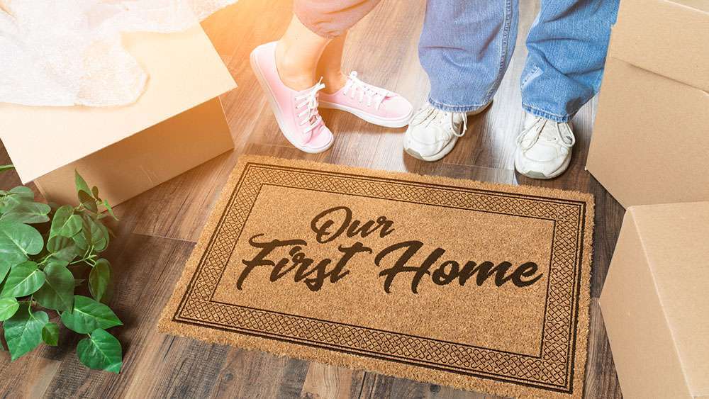 From Renter to Owner: The Essential Guide for First-Time Homebuyers Moving boxes and a welcome mat in young couple's first home